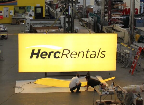 Technicians inspecting illuminated LED signage for Herc Rentals at Thomas Sign & Awning’s Clearwater facility, highlighting energy-efficient sign manufacturing