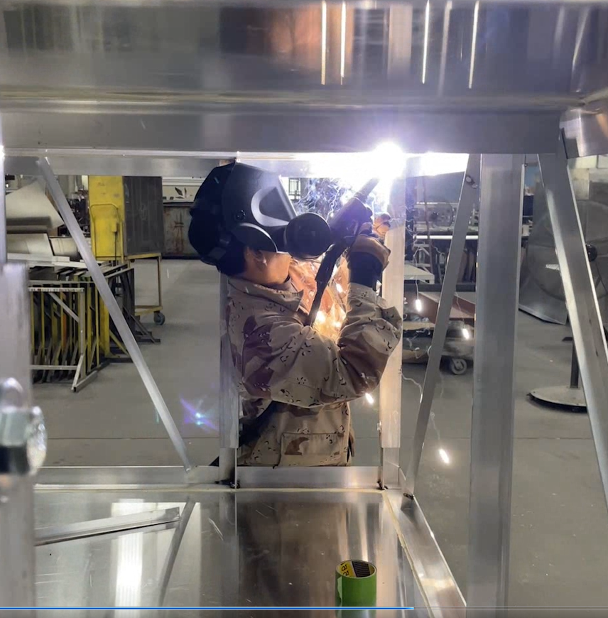 Technician welding a custom sign frame inside Thomas Sign & Awning’s Clearwater, Florida manufacturing facility