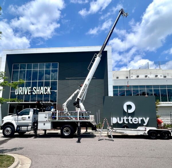 Crane installation of Puttery wall sign on commercial building exterior at Drive Shack location