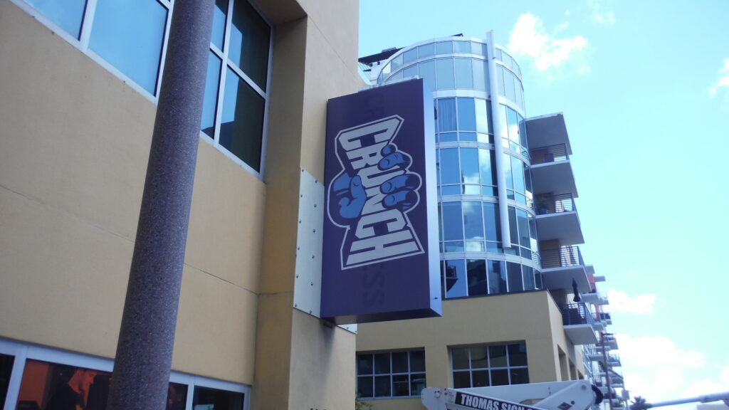 Exterior blade sign projecting from building to identify gym location and improve visibility