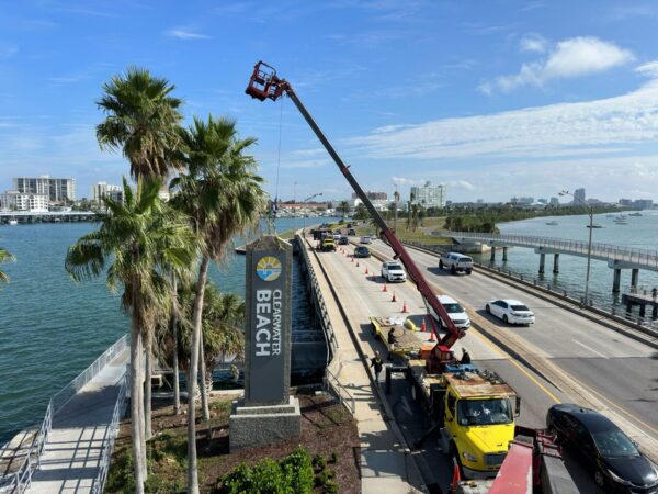 Monument sign installation using crane at Clearwater Beach entrance on waterfront roadway