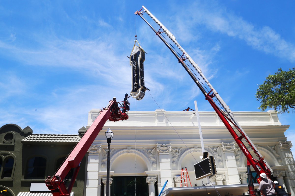 Commercial sign installation using crane to mount large exterior sign on building facade