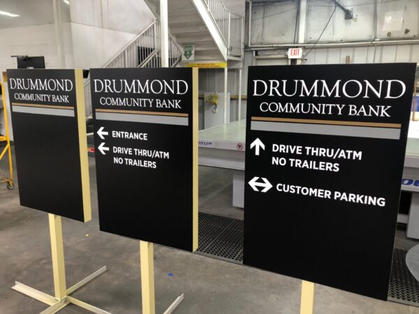 Wayfinding sign for bank showing directions to entrance, drive thru ATM, and customer parking