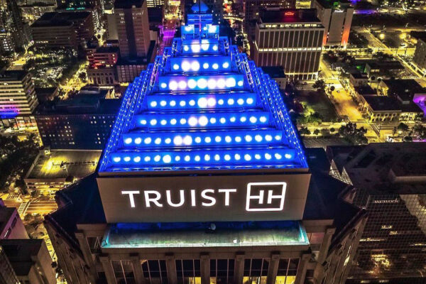 High-rise building sign for Truist illuminated at night on top of downtown office tower