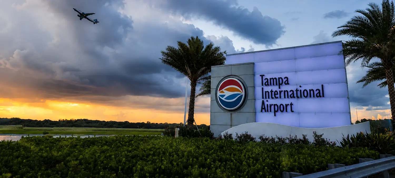 Illuminated Tampa International Airport monument sign at entrance during sunset