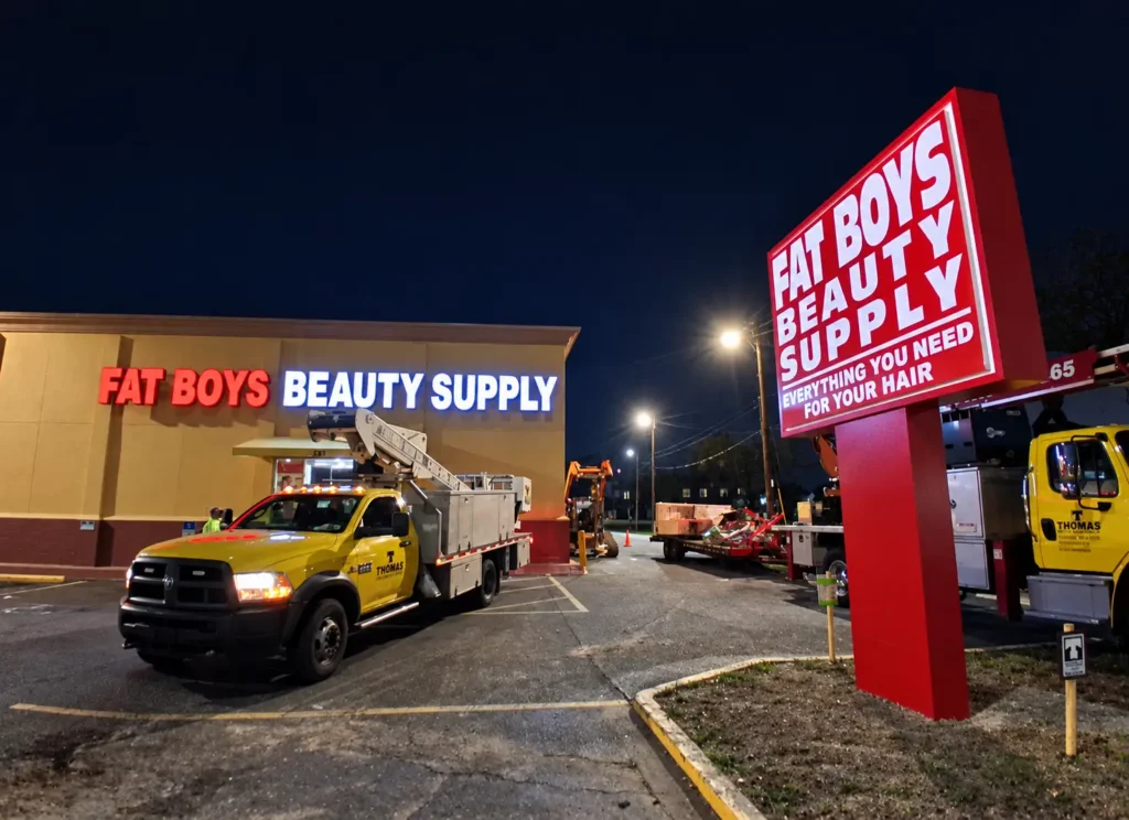 Illuminated Fat Boys Beauty Supply channel letters and red pylon sign at night in St. Petersburg, Florida