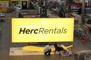 Technicians inspecting illuminated LED signage for Herc Rentals at Thomas Sign & Awning’s Clearwater facility, highlighting energy-efficient sign manufacturing